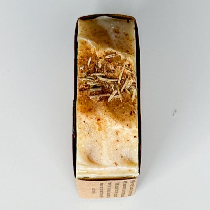 Birds eye view of the top He Knows bar. White with orange zest and powder as well as dried rosemary lay in the center of the top of the bar.