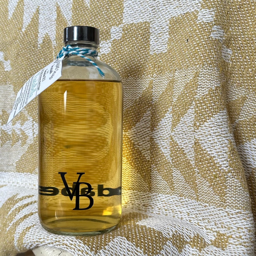 16 oz clear Glass bottle with black lid filled with honey colored liquid hand soap, tag hanging on the left side, yellow gold and white background.