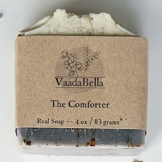 Purple bottom, white top bar with kraft paper product sleve centered on bar.  Black ink prints the brand logo, "The Comforter" and "Real Soap -- 4 oz / 113 grams*"