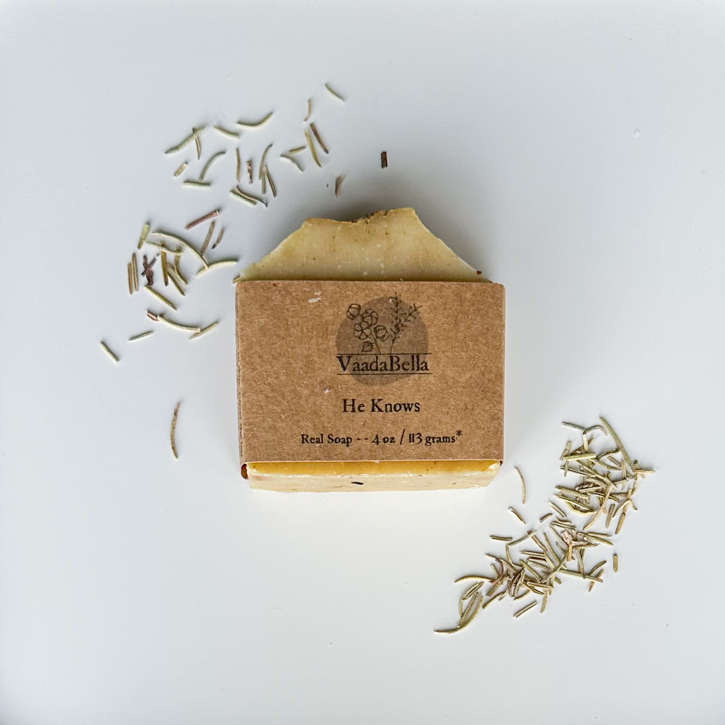 Green bottom, white top bar with kraft paper product sleeve centered on the bar.  Dried rosemary at the top left and bottom right of the bar.