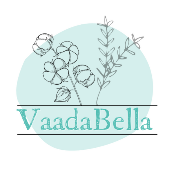 teal irregular circle sits behind bolder letting "VaadaBella."  Letters have a line above and below which extend just outside of the circle.  Above the parallel lines is a natural cotton branch to the left and a simple herb branch to the right, both of which extend past the irregular circle.